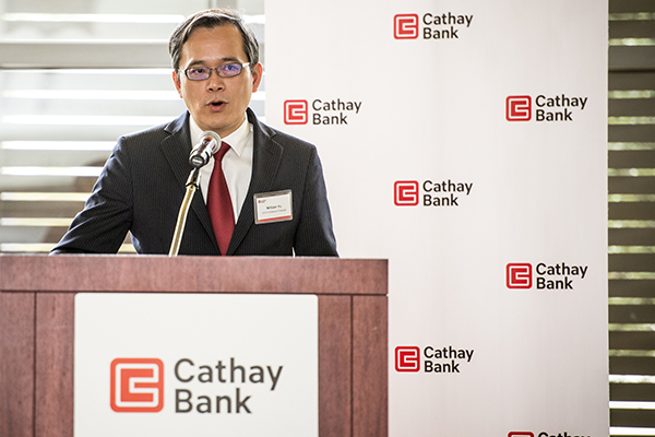 Dr. William Yu, Economist of UCLA Anderson Forecast, speaking at a podium.