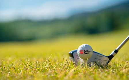 A close-up of a National Graphic Islamic Bank-branded golf ball and golf club on a golf course
